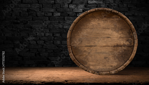 A brown hardwood barrel rests on a wooden table against a brick wall, blending in with the landscape in its tints and shades, illuminated by the darkness around