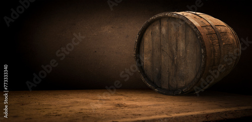 A brown wooden barrel, made of hardwood, sits atop a circular wooden table at a winery. The natural material blends into the warm temperature, showcasing tints and shades of wood stain