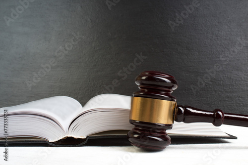 Law concept - Open law book with a wooden judges gavel on table in a courtroom or law enforcement office isolated on white table. Copy space for text.