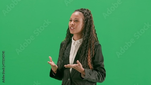 Young female reporter isolated on chroma key green screen background. African american woman tv news host walking and talking. Half turn.