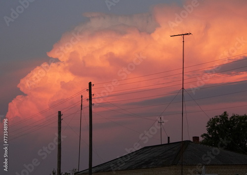 Clouds in the sky over the roofs of houses at sunset in summer