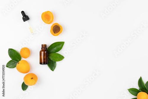 Natural Cosmetic Apricot Oil. Dropper lid with pipette and bottle on white background with fresh peach fruits and leaves. Top view, layout, place for text. photo