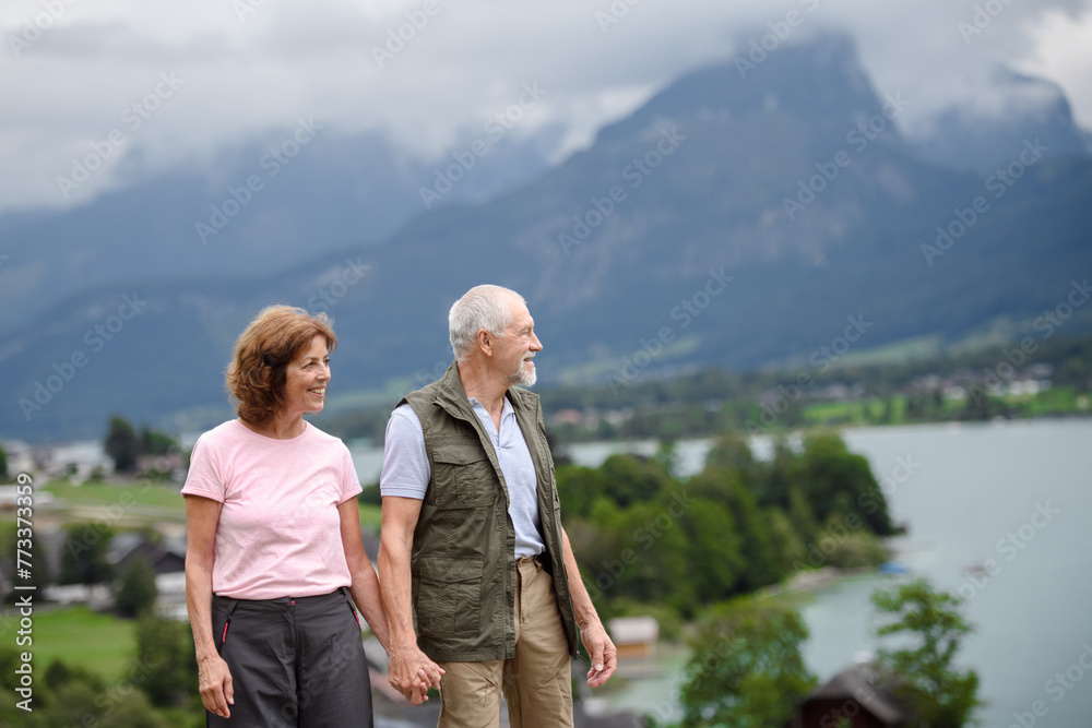 Active elderly couple hiking together in spring mountains. Senior tourists enjoying nature and exercising