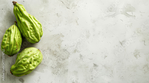 Fresh chayote squash on a white textured surface. photo