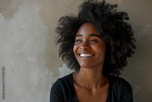 Portrait of a joyful young woman with curly hair smiling against a neutral background. photo