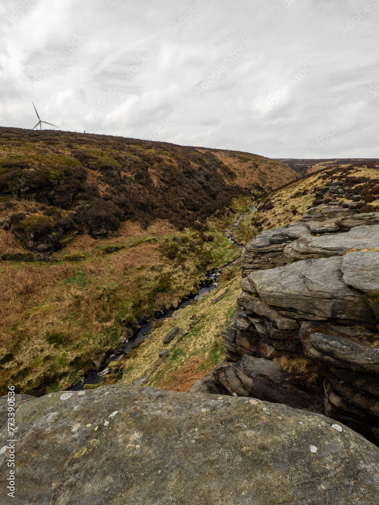 Fototapeta premium Fields, hills, mountains and a large rock in the foreground. Yorkshire moors. Wild and bleak. Rocky hill top scenic view at dusk