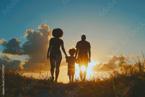 Silhouette of black African American couple and child walking at sunset
