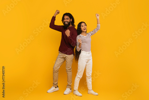 Man and woman with fists pumped on yellow background