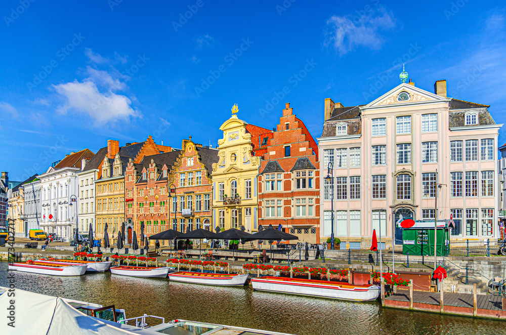 Ghent city historical center, tourists boats near Korenlei Corn Wheat Quay on Leie river bank, row of old colorful buildings on Lys river embankment, East Flanders province, Flemish Region, Belgium