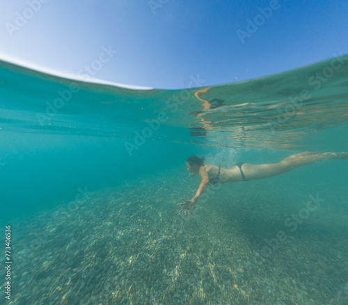 Sea summer landscape. Travel and Holiday concept. A brunette woman diving into blue sea water. Underwater photography of sport activity