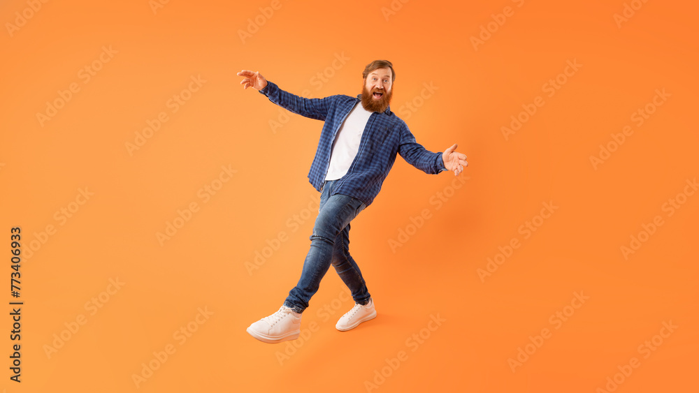 Positive redhaired guy with beard fooling posing on orange background