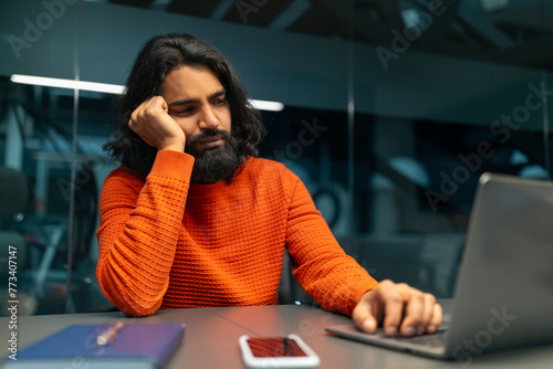 Man bored at work on laptop photo