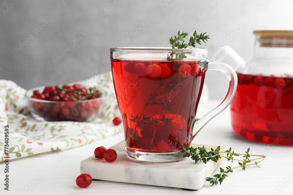 Tasty hot cranberry tea with thyme and fresh berries in glass cup on white wooden table - obrazy, fototapety, plakaty 