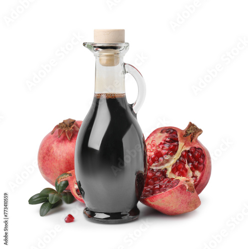 Tasty pomegranate sauce in bottle, fruits and branch isolated on white