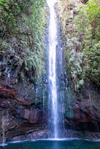 Scenic view of majestic waterfall Cascata das 25 Fontes along idyllic Levada walk in evergreen subtropical Laurissilva forest of Rabacal  Madeira island  Portugal  Europe. Clear plunge basin below