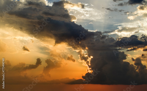 Bright sunset with setting sun behind vivid orange and yellow clouds