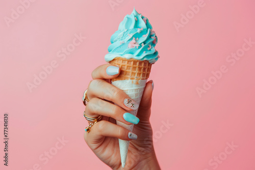 A woman's hand holding a pink ice cream cone in pink background