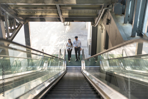 Two professionals in conversation while riding an escalator © Naypong Studio