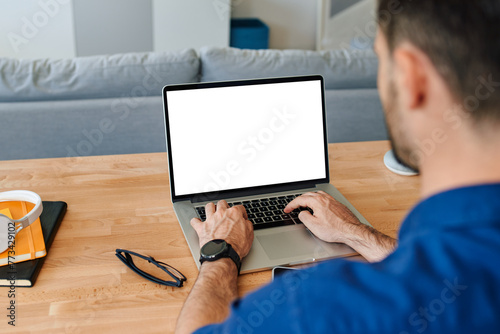 Closeup of man using laptop at home with blank empty screen