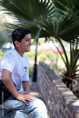 Niño latinoamericano feliz recargado de una barda al aire libre photo