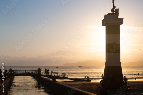 Tourists strolling during the late afternoon in Santos, on channel 6, with the lighthouse in the foreground. photo