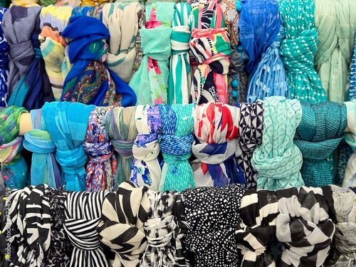 Collection of colorful knotted scarves hanging in rows in a boutique