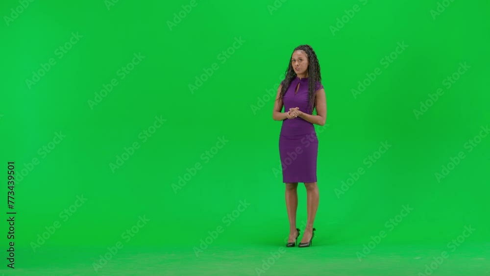Female in dress isolated on chroma key green screen background. Full shot african american woman tv news host standing talking looking at camera.