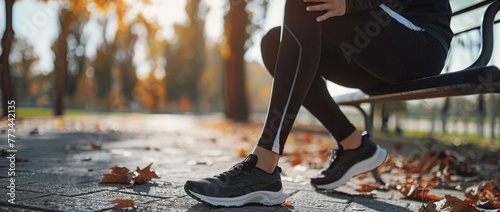 A young woman in black leggings and running shoes is sitting on a bench, holding her leg in pain after a workout or training at the park Generative AI