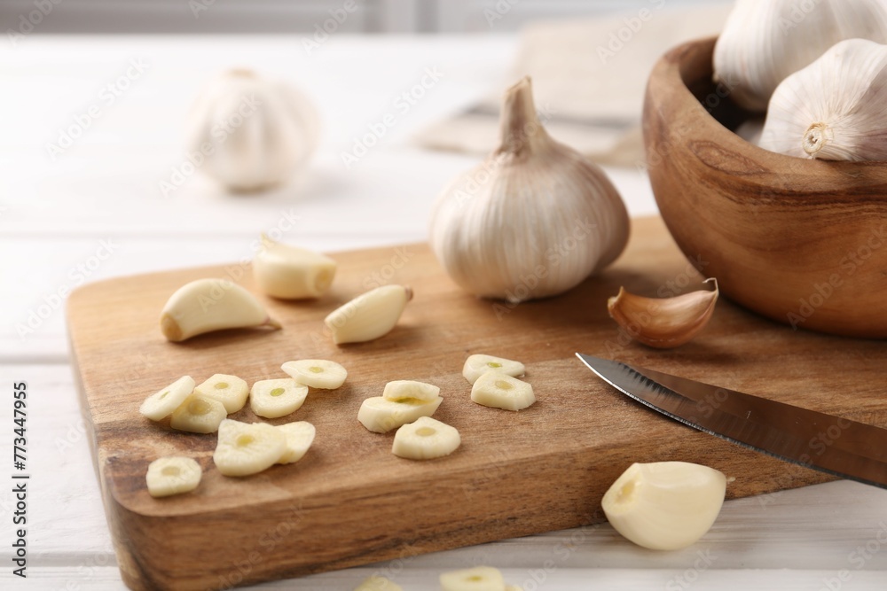 Aromatic cut garlic, cloves and bulbs on white wooden table, closeup Aromatic cut garlic, cloves and bulbs on white wooden table, closeup