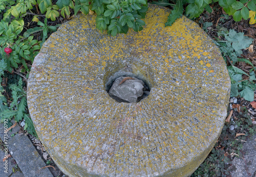 Alter Mühlstein in einem Park, mit Flechten überwachsen photo