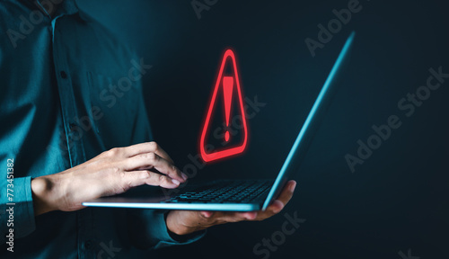 firewall, network, server, spyware, theft, information, stealing, danger, system, phishing. A man is holding a laptop with a red exclamation point on the screen. Concept of urgency or danger.