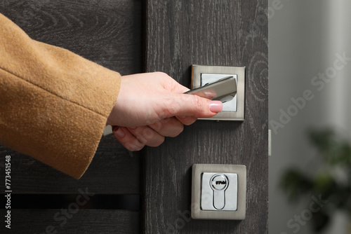 Woman opening wooden door indoors, closeup of hand on handle photo