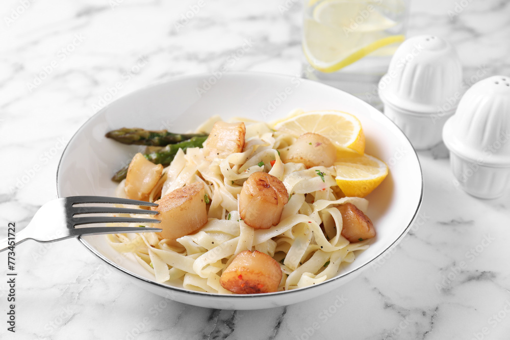 Delicious scallop pasta with asparagus and lemon on white marble table
