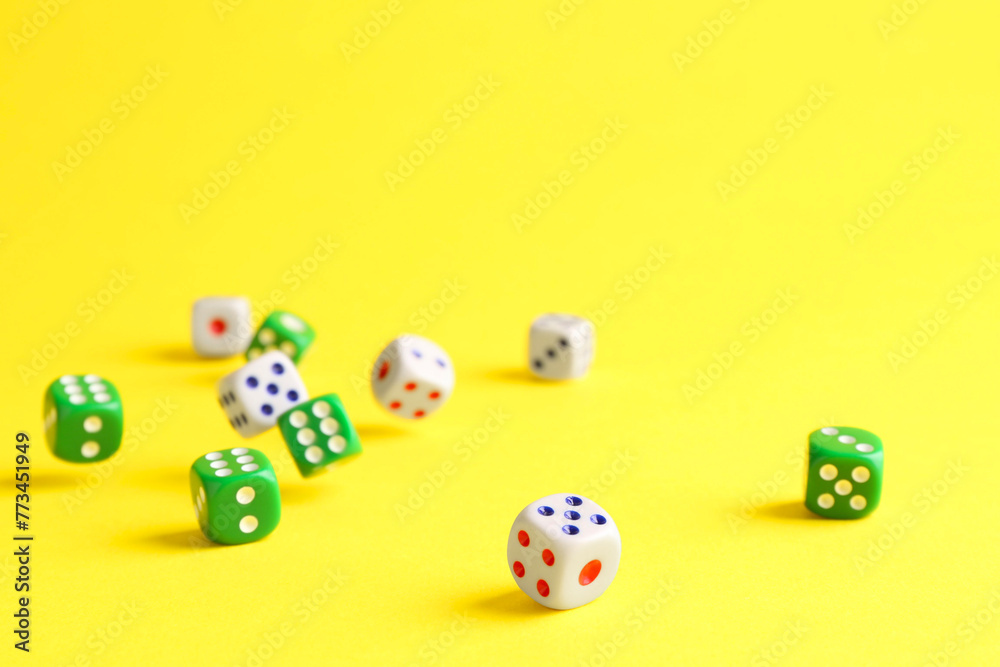 Many color game dices falling on yellow background Many color game dices falling on yellow background