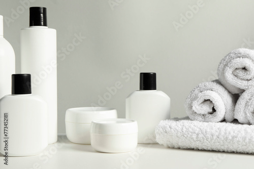 Different bath accessories and towels on white table against grey background