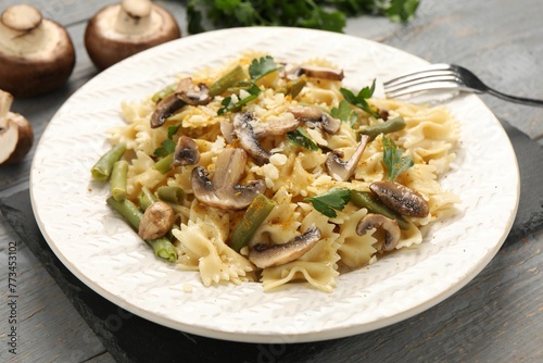 Vegetarian pasta with mushrooms, parsley, string beans and cheese on grey wooden table, closeup