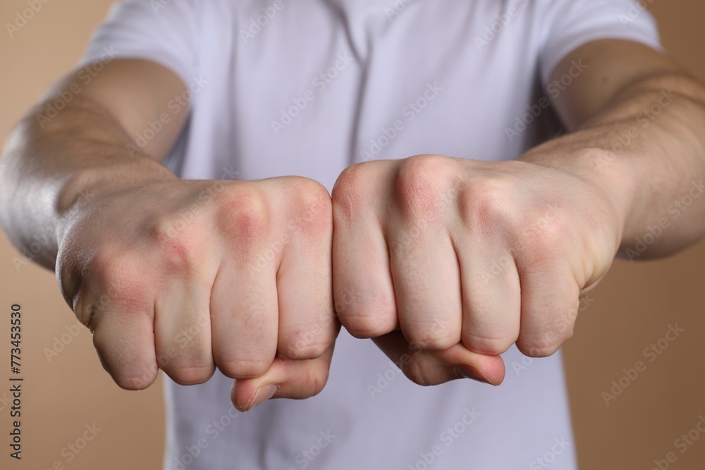 © New Africa - Man showing fists with space for tattoo on beige background, selective focus © New Africa - Man showing fists with space for tattoo on beige background, selective focus