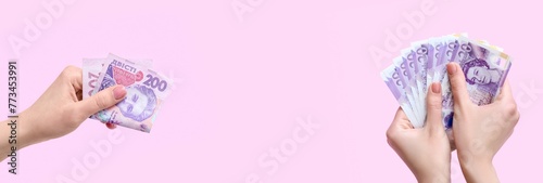Hands with hryvnia and pound sterling banknotes on pink background photo