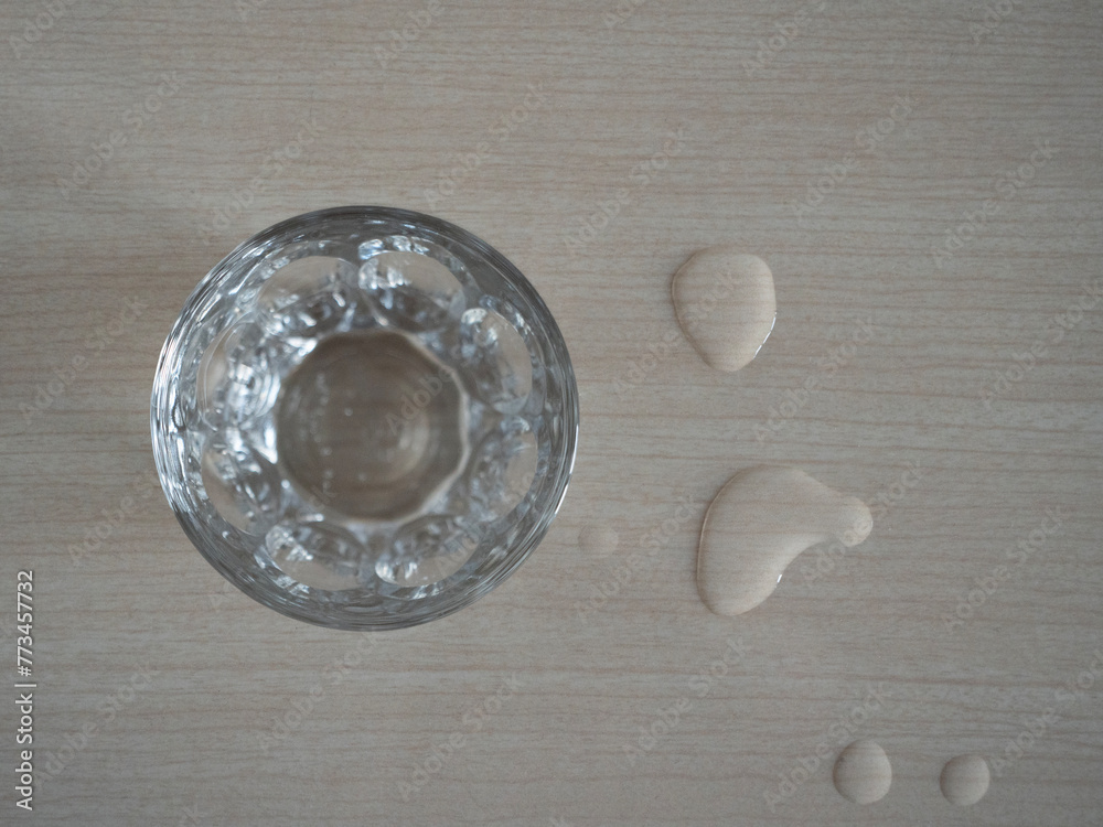 drinking glass full of water with drops spilled on the table, water waste concept drinking glass full of water with drops spilled on the table, water waste concept