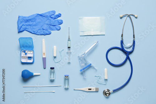 Gynecological speculum with stethoscope, pregnancy test and medical tools on blue background photo