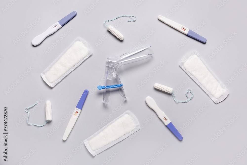 Gynecological speculum with pads, tampons and pregnancy tests on white background Gynecological speculum with pads, tampons and pregnancy tests on white background