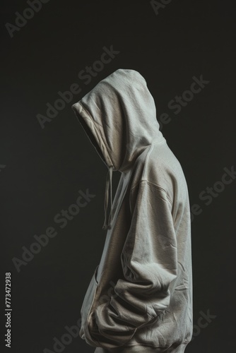 A man in a hoodie standing in front of a black background. Suitable for various projects