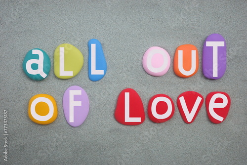 All out of love, creative slogan composed with hand painted multi colored stone letters over green sand