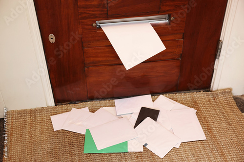 Wooden door with mail slot and many envelopes indoors photo