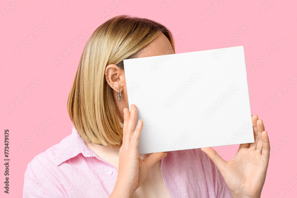 Woman with multiple ear piercing and blank paper sheet on pink background - obrazy, fototapety, plakaty 