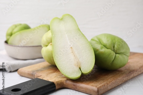 Cut and whole chayote on white tiled table, closeup photo