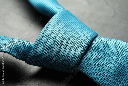 One light blue necktie on grey textured table, closeup