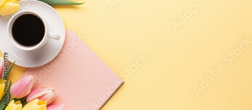 Coffee cup and book placed on a bright yellow background, creating a cozy and inviting atmosphere