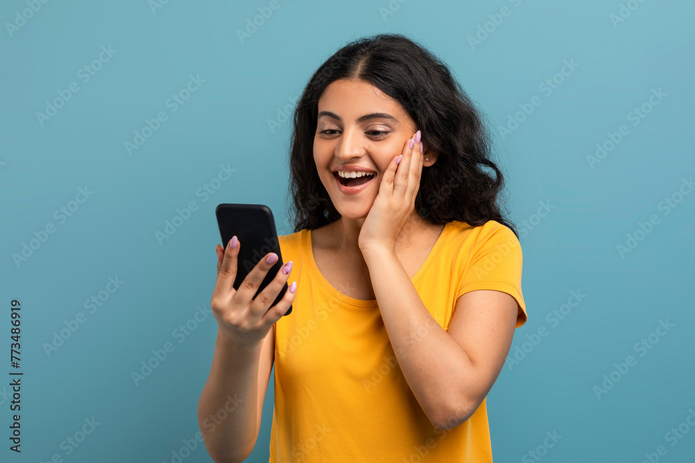 Excited lady with smartphone on teal