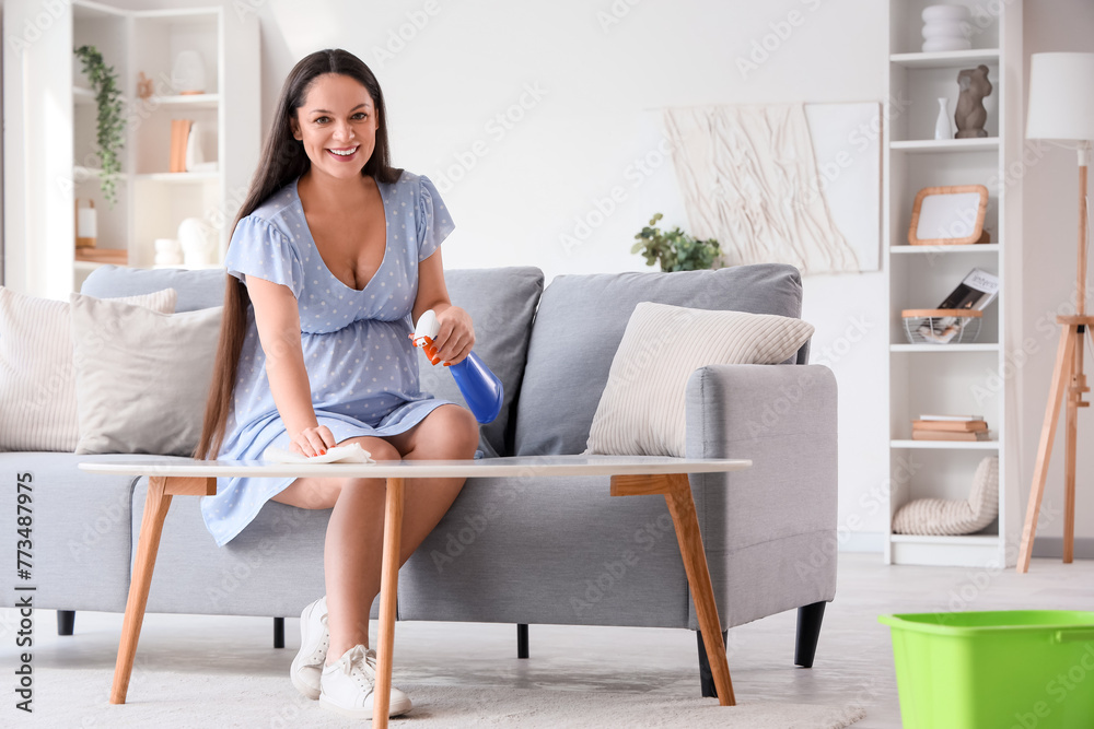 Young pregnant woman cleaning coffee table at home Young pregnant woman cleaning coffee table at home